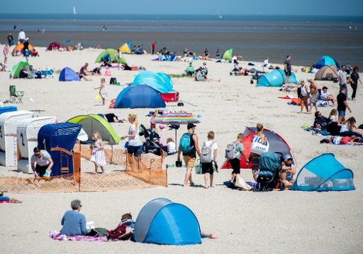 30 May 2020, Lower Saxony, Schillig: Numerous tourists sit on the beach of the village in the district of Friesland. At Whitsun, numerous holidaymakers are expected at the coast of Lower Saxony and the islands. Photo: Hauke-Christian Dittrich\/