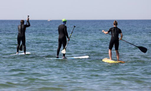 02 June 2020, Mecklenburg-Western Pomerania, Warnemünde: Stand up paddlers are out and about on the Baltic Sea. In Mecklenburg-Vorpommern the warmest day of the year so far is expected on 02.06.2020 with over 25 degrees. Photo: Bernd Wüstneck\/dpa-Zentralbild\/