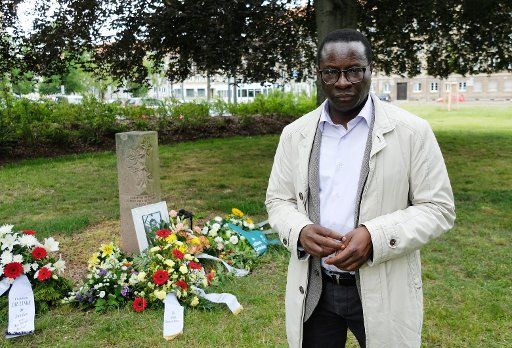11 June 2020, Saxony-Anhalt, Dessau-Roßlau: Karambolage Diaby, SPD member of the Bundestag, stands at a memorial stone in the city park of Dessau. The memorial commemorates Alberto Adriano- the 39-year-old Mozambican was beaten up by neo-Nazis on 11.06.2000, he died of his injuries three days later. With a silent remembrance it was remembered. Photo: Sebastian Willnow\/dpa-Zentralbild
