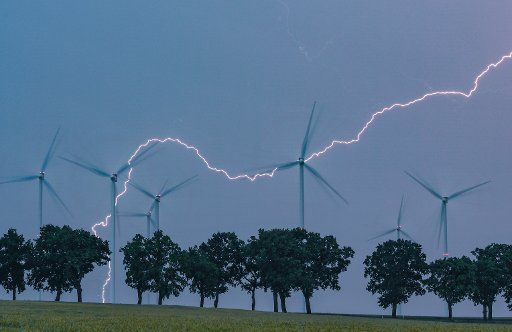 13 June 2020, Brandenburg, Petersdorf: A flash of lightning illuminates the evening sky above the landscape with wind turbines and an avenue in the Oder-Spree district. Last night thunderstorms swept over the state of Brandenburg. Photo: Patrick Pleul\/dpa-Zentralbild