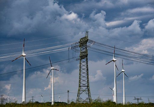 29 June 2020, Brandenburg, Brieselang: A power pole and wind turbines can be seen on a field not far from Brieselang in Brandenburg. Photo: Paul Zinken\/dpa-Zentralbild