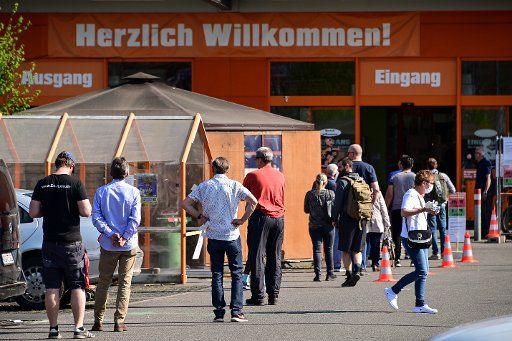 16 April 2020, Hessen, Kassel: People stand in line in front of a DIY store in compliance with the distance rule. The corona rules in the retail trade should be carefully relaxed. Photo: Uwe Zucchi\/
