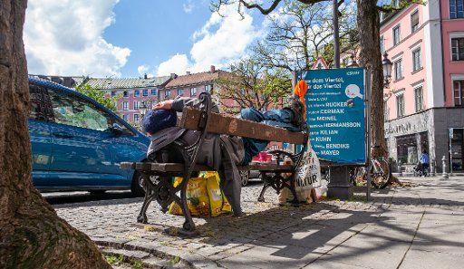 19 April 2020, Bavaria, Munich: A homeless man lies on a park bench on Gärtnerplatz in the city centre. Photo: Peter Kneffel\/