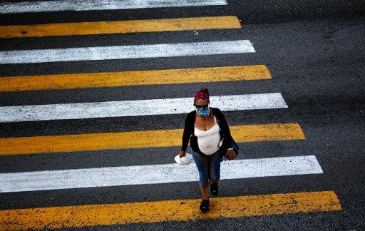 21 April 2020, Cuba, Havanna: A woman in a face mask walks across the crosswalk. In contrast to other countries, the Cuban government has not imposed a curfew, but has called on the population to stay at home if possible. Cuba has registered 1137 Covid-19 infected persons. At least 38 people are reported to have died from the virus. Photo: Guillermo Nova\/