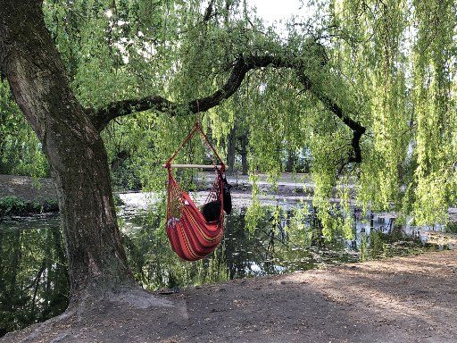 23 April 2020, Hamburg: A woman relaxes in a hammock by the pond in the Eimsbüttel district. Photo: Marcus Brandt\/