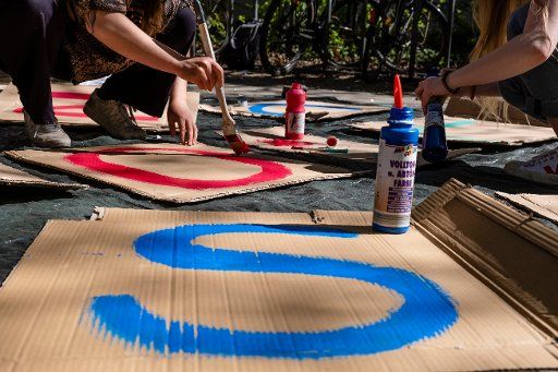 24 April 2020, Schleswig-Holstein, Kiel: Members of the Fridays for Future Ortsgruppe Kiel paint letters on pieces of cardboard. Due to the corona pandemic, there are only two small group actions during the fifth global climate strike this time in Kiel. Photo: Frank Molter\/
