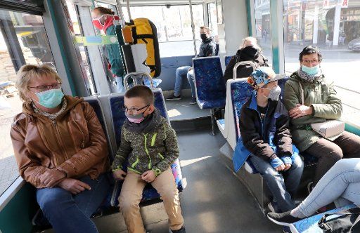 27 April 2020, Mecklenburg-Western Pomerania, Rostock: Passengers are sitting in a tram with mouth-nose covers. From 27.04.2020 it will be mandatory in Mecklenburg-Vorpommern to wear a mouth-nose cover when shopping as well as in local public transport including taxis. Photo: Bernd Wüstneck\/dpa-Zentralbild\/