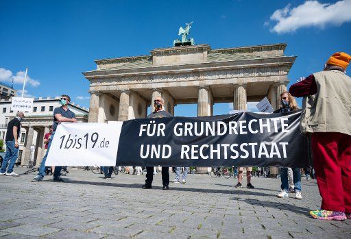09 May 2020, Berlin: Demonstrators hold a banner in front of the Brandenburg Gate with the inscription "1bis19.de - Für Grundrechte und Rechtsstaat". The organizers demand clear and reasonable goals and measures in the fight against the pandemic. Photo: Christophe Gateau\/