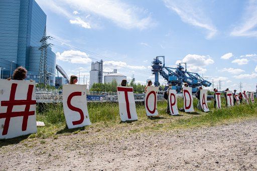 17 May 2020, North Rhine-Westphalia, Datteln: Participants of the demonstration "Stop dates 4! For Climate Justice Worldwide" stand in front of the coal-fired power station with letters on which: "#Stop Dates 4" is written. Photo: Guido Kirchner\/