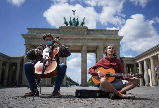 17 May 2020, Berlin: Johannes (l) and Bo play music and demonstrate in front of the Brandenburg Gate. They demand the opening of the refugee camp Moria. Photo: Jörg Carstensen\/