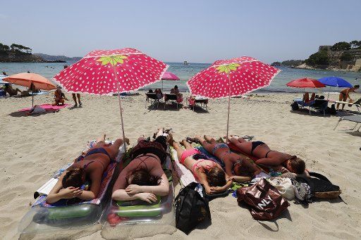 01 August 2020, Spain, Paguera: A family from Frankfurt is sunbathing on the beach on the island of Mallorca. Photo: Clara Margais\/dpa
