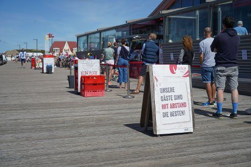 03 August 2020, Sylt, Wenningstedt-Braderup: Numerous vacationers stand in bright sunshine near Gosch to buy a fish roll. Photo: Jörg Carstensen\/dpa