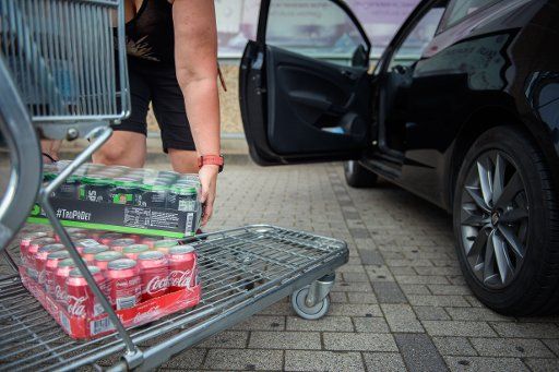 20 August 2020, Schleswig-Holstein, Flensburg: A woman loads several pallets of deposit-free beverage cans into her car outside a supermarket in Flensburg on the German-Danish border. (to dpa "The German-Danish can dilemma") Photo: Gregor Fischer\/dpa