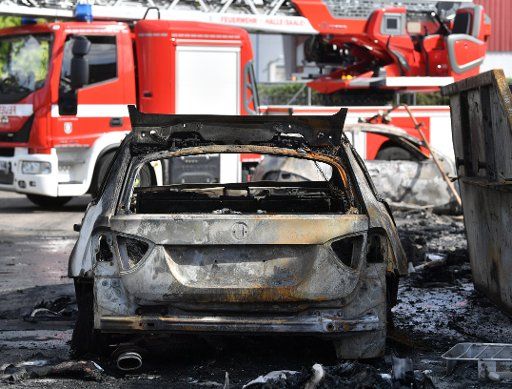 30 June 2020, Saxony-Anhalt, Halle (Saale): A burnt-out car stands in front of a fire brigade in an industrial park. After a major fire, the damage in the park is considerable. Photo: Hendrik Schmidt\/dpa-Zentralbild