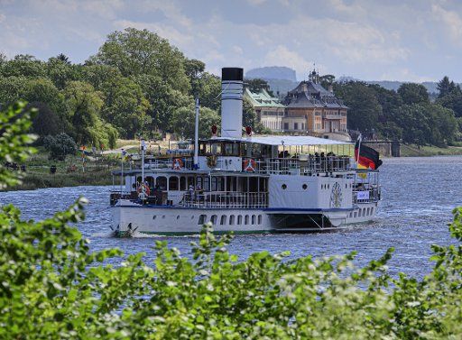 06 July 2020, Saxony, Dresden: The historic paddle steamer "Leipzig" of the Saxon Steamship Company is travelling on the Elbe towards the city centre. In the background you can see Pillnitz Castle and the Lilienstein in Saxon Switzerland. Photo: Robert Michael\/dpa-Zentralbild