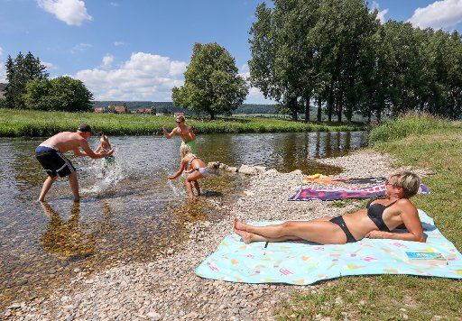 09 July 2020, Baden-Wuerttemberg, Riedlingen-Daugendorf: People splash each other with water in the shallow waters of the Danube in sunny weather. Photo: Thomas Warnack