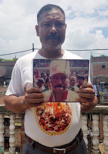 16 July 2020, Nepal, Bhaktapur: Ambulance driver Buddha Krishna Baga Shrestha holds an old photograph in his hand showing his tongue pierced with an iron needle during the Jibro Chedne Jatra, a tongue piercing festival. The 49-year-old is a local celebrity because he has played the demon at the festival for years. (to dpa "A demon helps Corona patients in Nepal") Photo: Roshan Sedhai\/dpa
