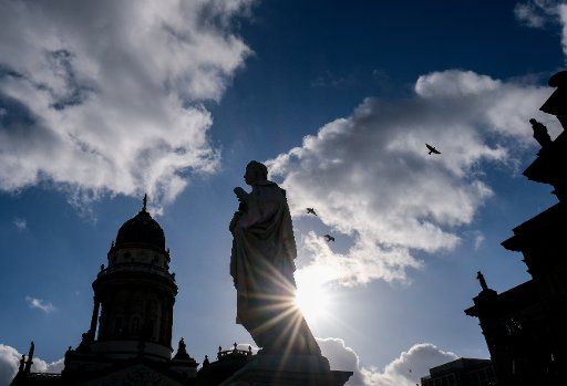 05 November 2020, Berlin: The Deutsche Dom (l-r), the Schiller Monument and the Konzerthaus on Gendarmenmarkt can be seen as silhouettes against clouds and blue sky in sunny weather. Photo: Jens Kalaene\/dpa-Zentralbild\/dpa