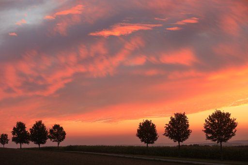 16 September 2020, Baden-Wuerttemberg, Uttenweiler-Offingen: Shortly before sunrise the sky glows reddish over the hilly landscape. Photo: Thomas Warnack\/dpa