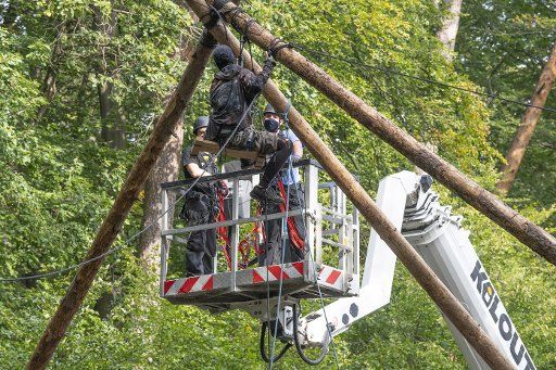 16 September 2020, Hessen, Dannenrod: The police are clearing barricades of forest squatters in the Dannenröder Forst in Central Hesse. An activist is sitting on a platform built of trunks while police are trying to reach her from a lifting platform. The squatters are protesting against the expansion of the Autobahn 49. Photo: Boris Roessler\/dpa
