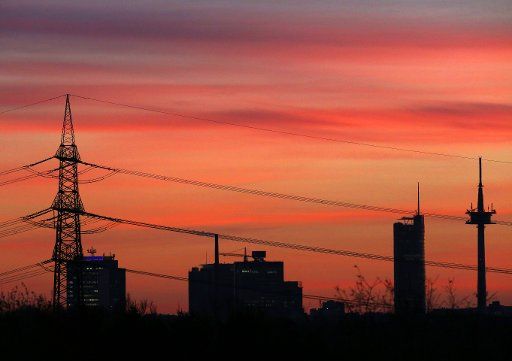 18 December 2020, North Rhine-Westphalia, Mülheim: Behind the administrative headquarters of large corporations, the sky is coloured red-orange at sunrise. After days of rain, plenty of sunshine is forecast for the next few days in NRW. Photo: Roland Weihrauch\/dpa