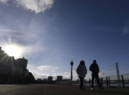 26 December 2020, North Rhine-Westphalia, Duesseldorf: Passers-by took advantage of the sunny weather to take a walk along the Rhine promenade on Boxing Day. Photo: Roberto Pfeil\/dpa
