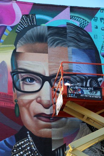 16 November 2020, US, New York: Artists are putting the finishing touches to a colorful painting on a house wall in the East Village in Manhattan. The large wall painting honors the prominent US judge Ginsburg, who died in September. (to dpa "Dead US Judge Ginsburg honoured with mural") Photo: Christina Horsten\/dpa
