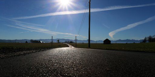 18 November 2020, Bavaria, Ruderatshofen: A road glistens with the panorama of the Alps against the sun. Photo: Karl-Josef Hildenbrand\/dpa
