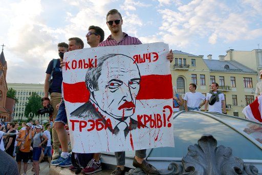 16 August 2020, Belarus, Minsk: "How much more blood will it take?" is written on the poster with the face of ruler Lukashenko held by a young man in Independence Square. (to dpa "Crises and conflicts: 2021 will not be an easy year in many places either") Photo: Ulf Mauder\/dpa