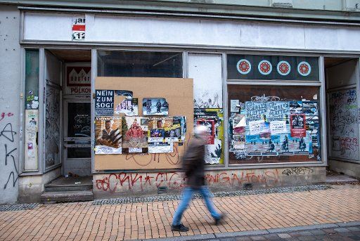 01 December 2020, Mecklenburg-Western Pomerania, Schwerin: A man walks past a vacant store. Old event posters for concerts or record fairs stick to the shop window panes. Photo: Jens Büttner\/dpa-Zentralbild\/dpa