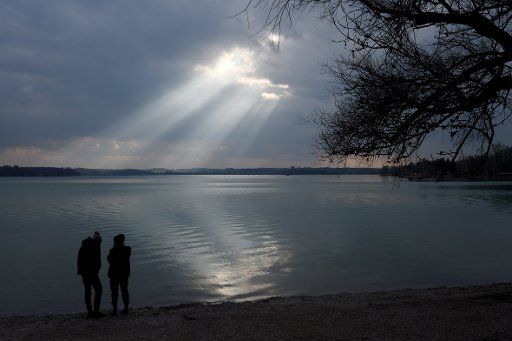 07 March 2021, Bavaria, Wörthsee: From the shore of the community of Wörthsee, rays of sunlight shining on the calm waters of Lake Wörthsee. With sunshine and a cold temperature, the weather invited for a weekend walk. Photo: Felix Hörhager\/dpa