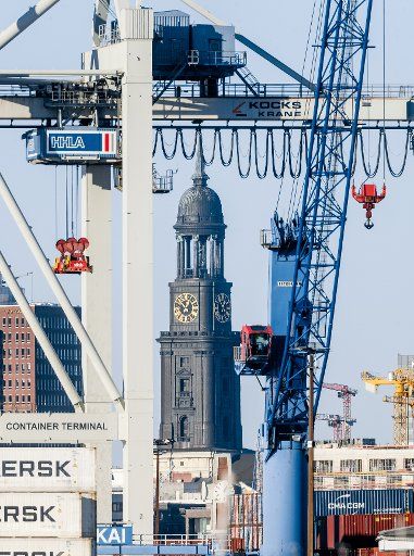 25 December 2020, Hamburg: The tower of the main church St.Michaelis, colloquially the Michel, can be seen through container cranes of the Hansa harbour. Photo: Markus Scholz\/dpa