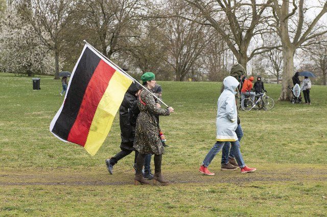 11 April 2021, Hessen, Frankfurt\/Main: Participants of the demonstration of the initiative "Querdenken" with a Germany flag. Photo: Boris Roessler\/dpa