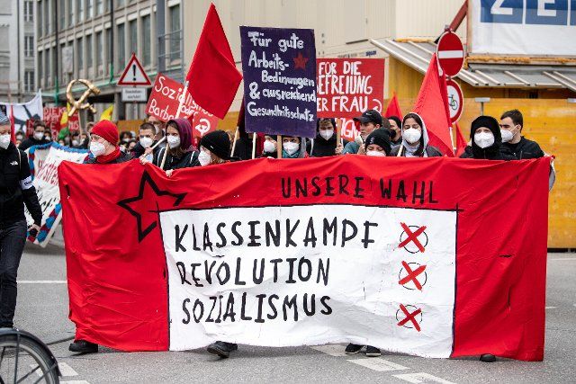 01 May 2021, Bavaria, Munich: Demonstrators carry their banner with the inscription "Our choice: class struggle, revolution, socialism" to Königsplatz at a rally of the German Trade Union Confederation (DGB) under the slogan "Solidarity is the future". Photo: Matthias Balk\/dpa