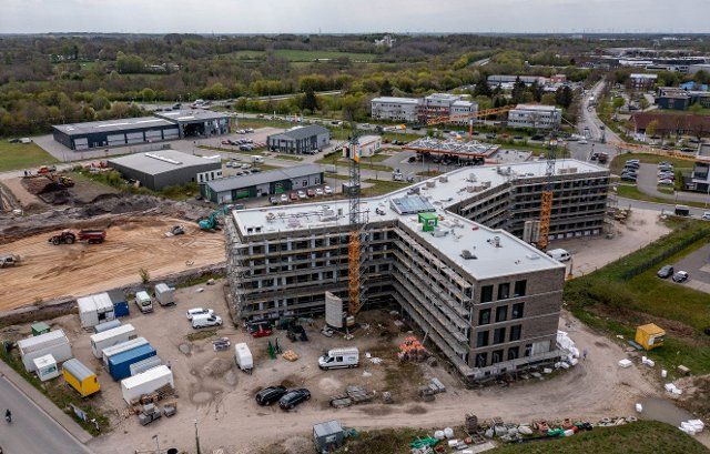 10 May 2021, Schleswig-Holstein, Flensburg: Cranes swing over a construction site in a commercial area in the south of Flensburg. The Chamber of Industry and Commerce in the north fears disadvantages from regulations against the sealing of areas. (Aerial photo with drone) Photo: Axel Heimken\/dpa