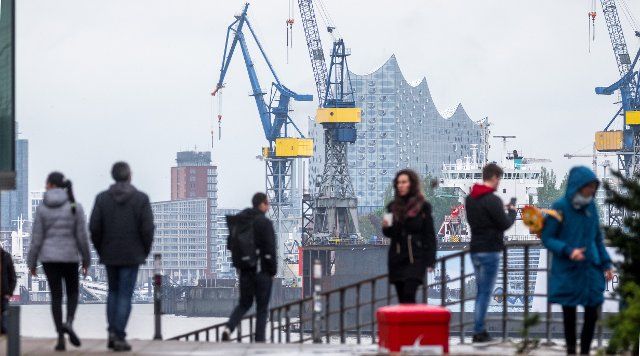 13 May 2021, Hamburg: In the drizzle, strollers look out from the wooden harbour at cranes and the Elbphilharmonie concert hall. Photo: Markus Scholz\/dpa