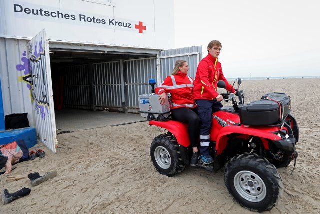 13 May 2021, Mecklenburg-Western Pomerania, Warnemünde: Gina Bretsch (l-r) and Benedict Leidecker of the water rescue start from the rescue tower at the Baltic Sea beach with the quad for a trip on the almost empty Baltic Sea beach. The lifeguards of the DRK Wasserwacht Rostock have resumed the guard duty of this year\