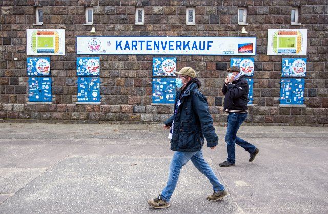 20 March 2021, Mecklenburg-Western Pomerania, Rostock: Football: 3. league, Hansa Rostock - Hallescher FC, 29. matchday: Season ticket holders walk past the closed sales booth for tickets at the Ostseestadion. FC Hansa Rostock is the first club to allow spectators back into the stadium. 777 visitors are allowed for the match of the soccer third league club against Halleschen FC. Beforehand, the season ticket holders, all of whom live in Rostock, must undergo quick tests. Photo: Jens Büttner\/dpa-Zentralbild\/dpa