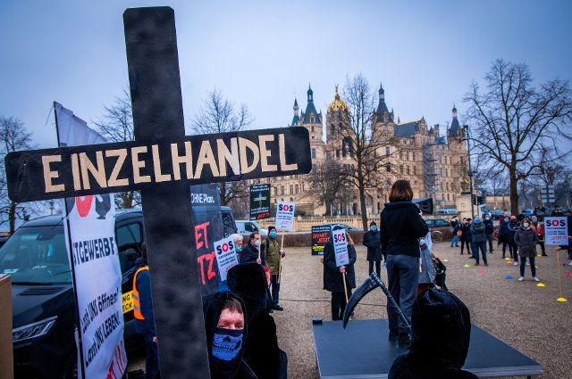 25 March 2021, Mecklenburg-Western Pomerania, Schwerin: Employees of the retail sector, dressed in the garb of the Grim Reaper, join restaurateurs and hotel operators in protesting against the ongoing Corona closures in front of the state parliament building in Schwerin Castle. The demonstrators demand equal treatment with other industries and a reversal of the decisions made at the federal-state meeting. Photo: Jens Büttner\/dpa-Zentralbild\/dpa