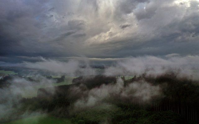 22 June 2021, Bavaria, Marktoberdorf: Swathes of fog drift through the cloudy Allgäu landscape in the evening light (aerial view with a drone). Photo: Karl-Josef Hildenbrand\/dpa