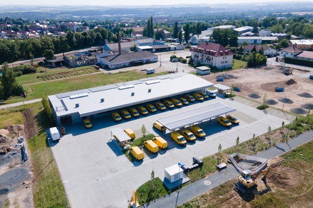 28 June 2021, Saxony, Pirna: Deutsche Post delivery vehicles are parked on the premises of a climate-neutral delivery base (ZSP) of Deutsche Post DHL Group. From the base, a letter and parcel supply for Pirna and the surrounding area is ensured. (Aerial view with drone) Photo: Sebastian Kahnert\/dpa-Zentralbild\/dpa