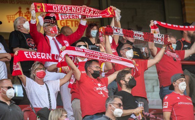 10 July 2021, Berlin: Football: Test matches, 1. FC Union Berlin white - 1. FC Union Berlin red, Stadion An der Alten Försterei. Union Berlin fans hold up scarves and wear face masks. The originally planned match against Dukla Prague could not take place due to traffic reasons. Photo: Andreas Gora\/dpa