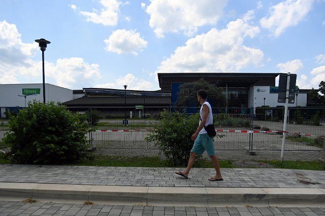 13 July 2021, Brandenburg, Schwedt: A passer-by walks past the cordoned-off area of the swimming pool "Aquarium". The roof of the swimming hall, which was closed for renovation work, had collapsed on 11.07.2021 for an unexplained reason. No one was injured.(to dpa "Mayor: Swimming hall roof was regularly checked") Photo: Stefan Csevi\/dpa-Zentralbild\/dpa