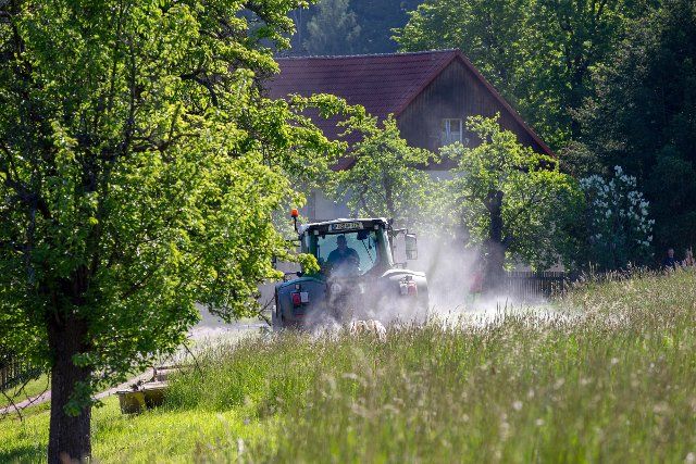 03 June 2021, Saxony, Kreischa: A farmer is driving his tractor with a mower attachment in a field in the morning. In the process, he passes a meadow orchard. Photo: Daniel Schäfer\/dpa-Zentralbild\/ZB