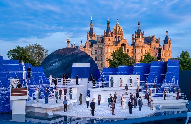 07 June 2021, Mecklenburg-Western Pomerania, Schwerin: Singers, actors and dancers perform in the musical "Titanic" on the stage of the Schwerin Castle Festival. The Mecklenburg State Theatre Schwerin starts the open-air season in Mecklenburg-Vorpommern on 11.06.2021 with the musical "Titanic". Up to 600 visitors are allowed to the performances with 65 actors on the stage between the castle and the state theatre. Actually, the grandstands can hold 2,000 spectators. Photo: Jens Büttner\/dpa-Zentralbild\/dpa