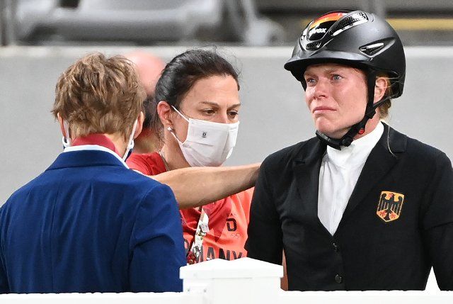 06 August 2021, Japan, Tokio: Modern Pentathlon: Olympics, Individual, Women, Jumping at Tokyo Stadium. Annika Schleu (r) of Germany reacts. behind her in the middle is national coach Kim Raisner (M). Her horse had refused to jump several times. Photo: Marijan Murat\/dpa