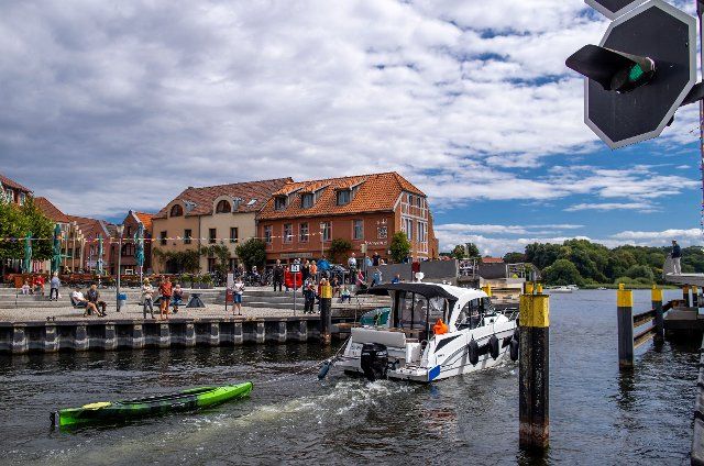 08 August 2021, Mecklenburg-Western Pomerania, Malchow: A motorboat drives through the open swing bridge into Lake Malchow. On the Mecklenburg Lake District, thousands of charter boats, private yachts or sailors are currently underway. (to dpa "Camping and boat rental companies demand practicable autumn solutions") Photo: Jens BÃ¼ttner\/dpa-Zentralbild\/dpa