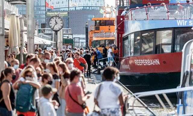 31 August 2021, Hamburg: Tourists go to the harbour cruise ships on the Landungsbrücken. Photo: Markus Scholz\/dpa