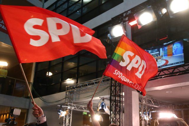 26 September 2021, Berlin: SPD supporters wave flags at the Willy Brandt House election party. Photo: Wolfgang Kumm\/dpa