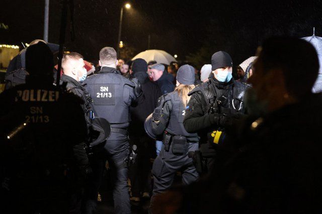 12 December 2021, Saxony, Bennewitz: Police officers observe several people forming a group. Gatherings with more than ten people are currently not allowed in Saxony because of the Corona situation. In several cities in Germany, people have again demonstrated against the Corona measures on the weekend. Photo: Tobias Junghannss\/TNN\/dpa